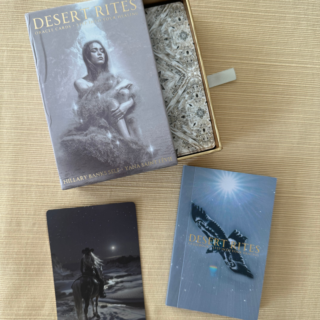Desert Rites Oracle 44-card deck with gold foil edges and full-color desert healing artwork. Card backs are visible within the box as pictured. Guidebook is displayed to the bottom right of the photo. One card face is shown in the bottom left of the image.