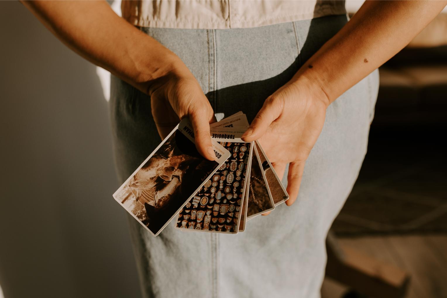 Woman holding The Outlaw Oracle Oracle Cards behind her back