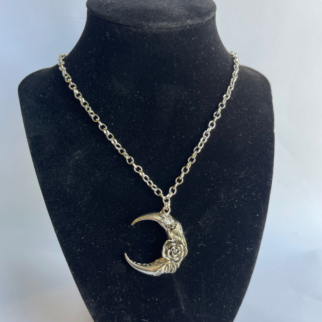 Crescent moon and rose necklace shown on neck form for size reference