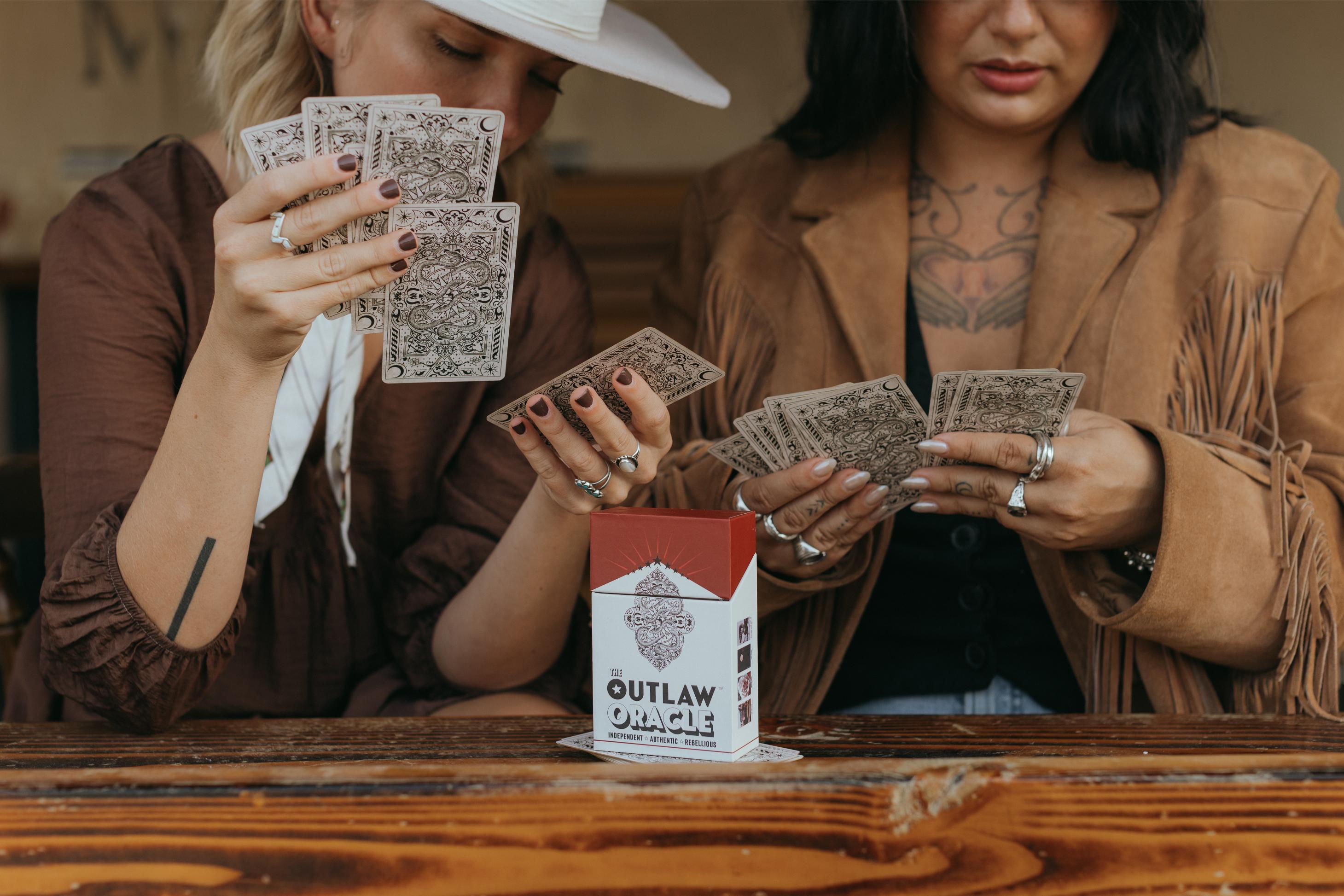 Women holding Oracle cards from The Outlaw Oracle Oracle Deck