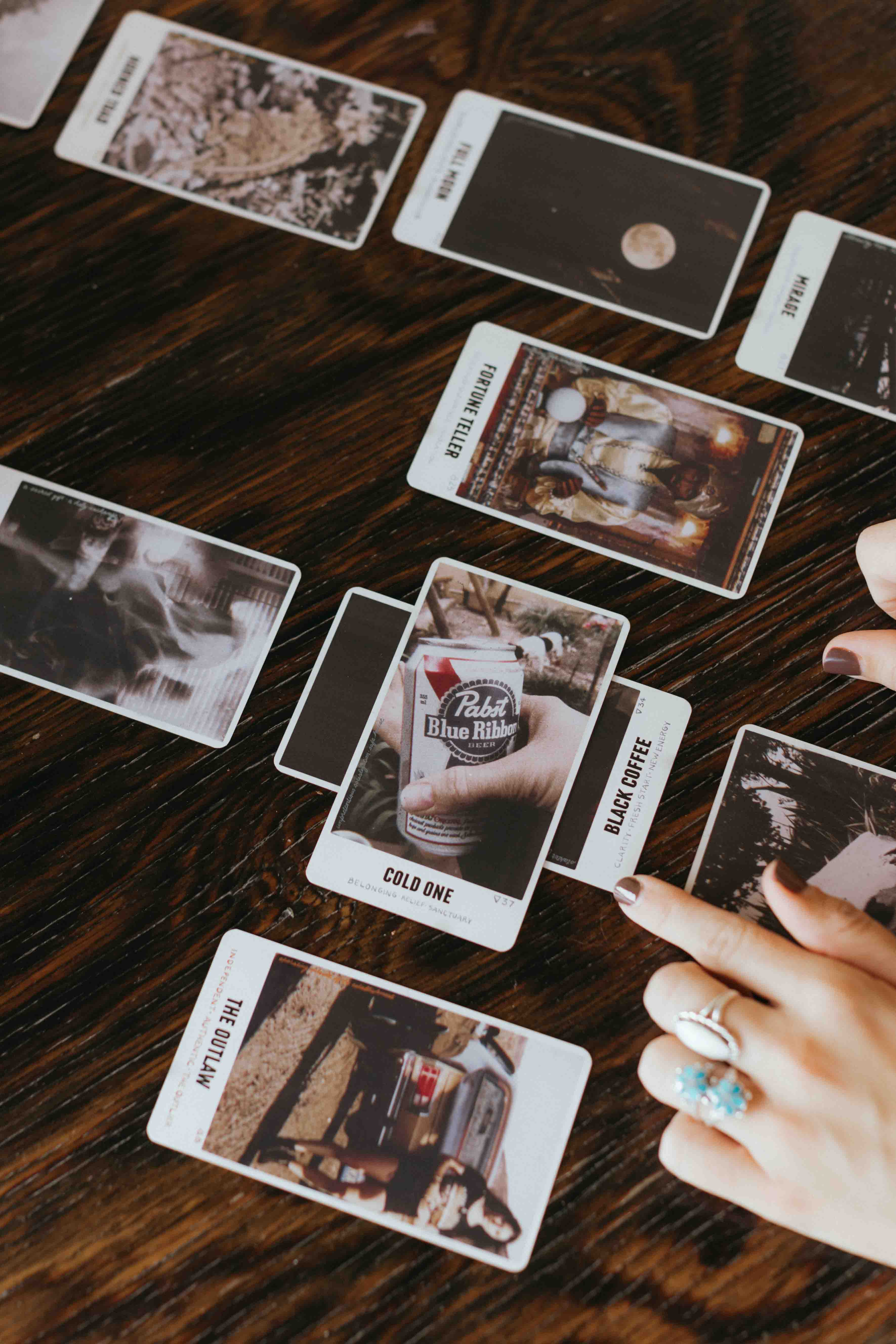 Outlaw Oracle cards arranged in reading layout showing card faces which feature American Gothic / Country and Western Images and Themes - as well as Outlaw Country song recommendations made in the guidebook for each card. 